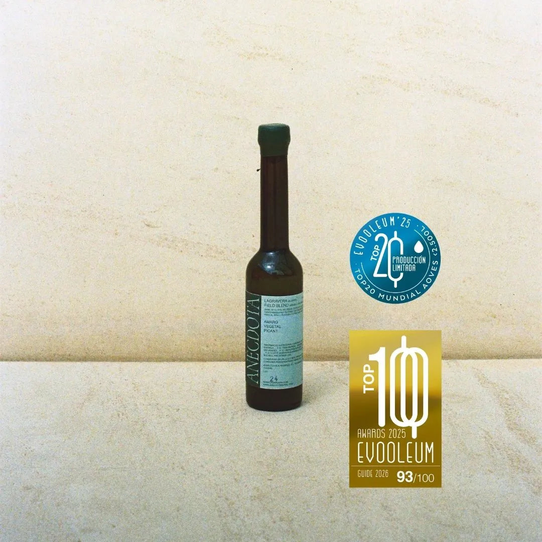 Sobre fondo gris de estudio una botella de aceite de oliva virgen extra La Gravera de la marca Anécdota. El envase predomina el color azul, tanto en el tapón de cera como en la etiqueta, son tonos azules tanto el fondo de la etiqueta como las letras.