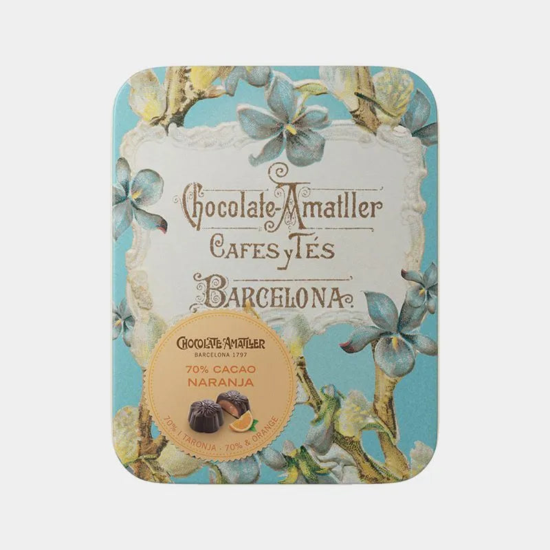 Lata metálica con decoración elegante de flores en tonos azules. Rellena de bombones en flor de chocolate negro y naranja