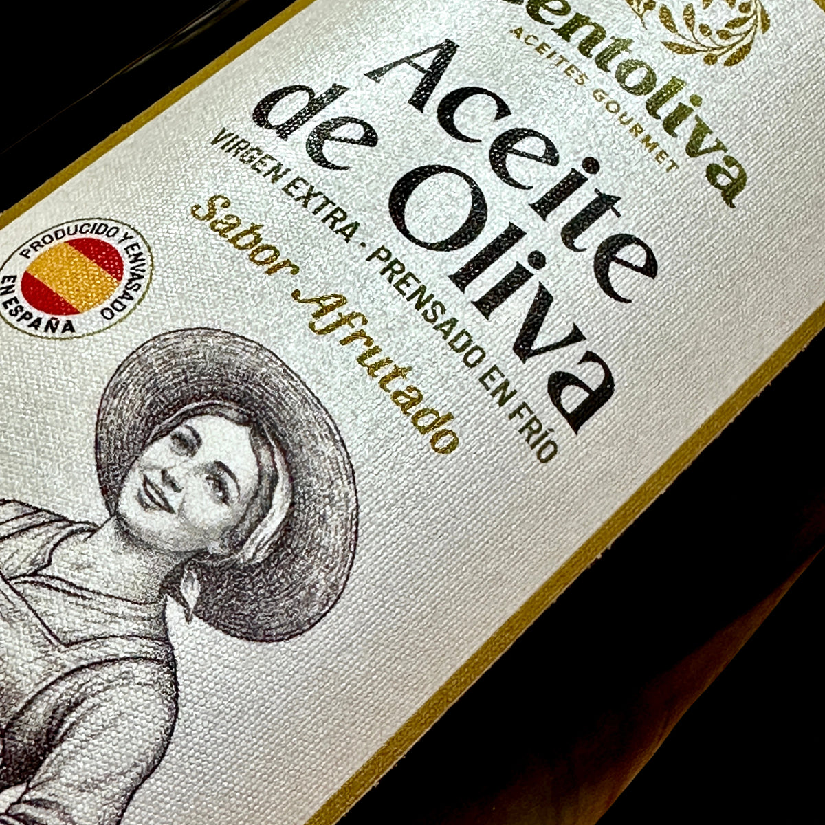 Primer plano de la botella de aceite de oliva Centoliva de la Región de Murcia, de diseño tradicional con etiqueta de ilustración de una aceitunera portando su cesta de aceitunas en D'12 Gourmet