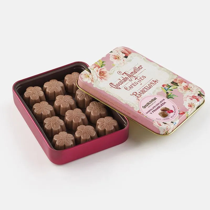 Lata de bombones de chocolate y frambuesa de Chocolates Amatller sobre fondo de estudio, mostrada abierta con su elegante diseño vintage en tonos rosas y florales, dejando ver en su interior los bombones en forma de flor en D'12 Gourmet