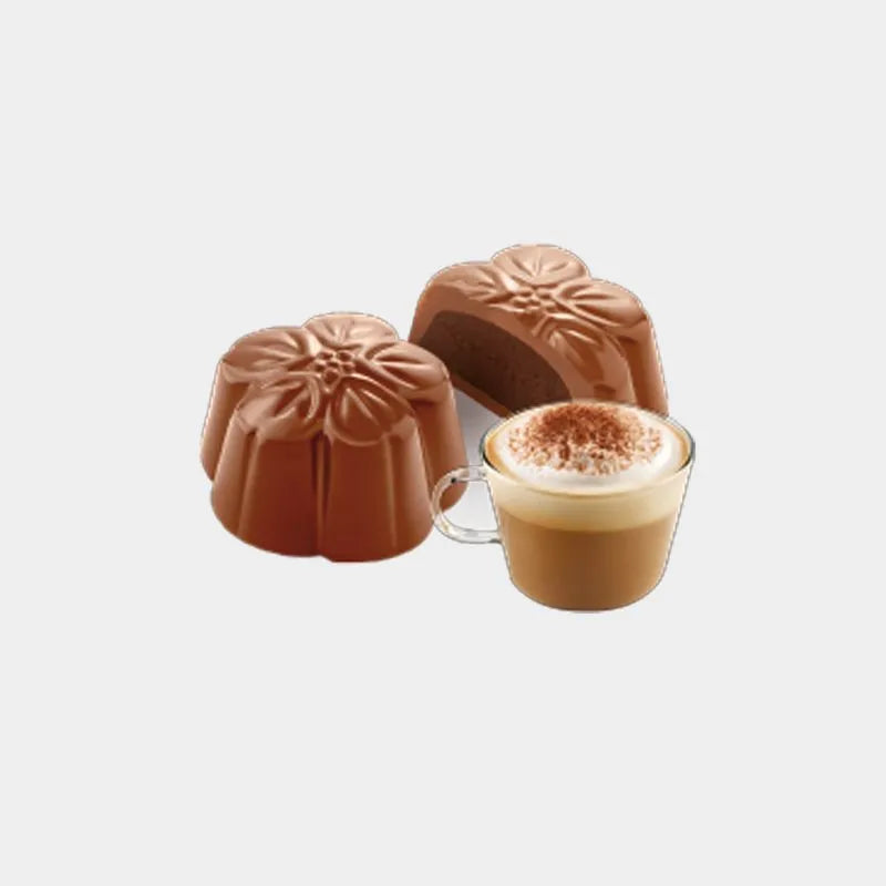 plano sobre fondo de estudio de dos bombones en forma de flor de Chocolates Amatller, uno entero mostrando su relieve y textura y otro partido por la mitad dejando ver su cremoso relleno de cappuccino, acompañados por un café capuccino en D'12 Gourmet