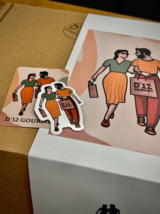 Caja especial para regalo de D'12 Gourmet. Caja de cartón con faja con el diseño de D'12 Gourmet, sobre esta caja también vemos una tarjeta y pegatina del logo del D12.