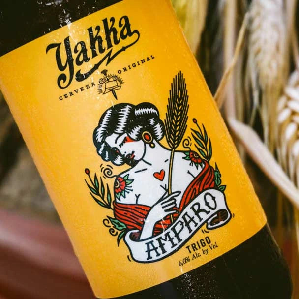 Primer plano de una botella de cerveza artesana de Murcia con etiqueta amarilla sobre fondo de espigas de trigo