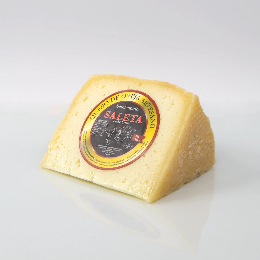 Cuña de queso semicurado de oveja de la casa Saleta sobre fondo de estudio, donde se aprecia su textura y color característicos, luciendo en el centro la etiqueta circular con la marca D'12 Gourmet