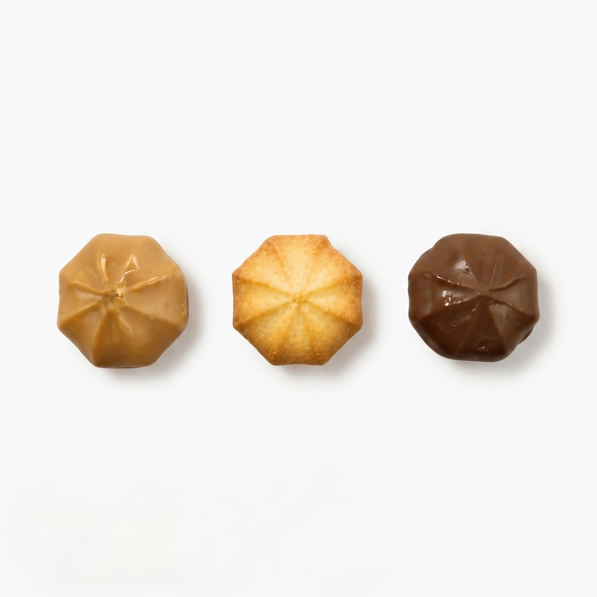 Imagen con las tres variedades de pastas de mantequilla que incluye la lata surtida de 200 g del Obrador Real: la pasta tradicional, una bañada en chocolate y otra bañada en caramelo.