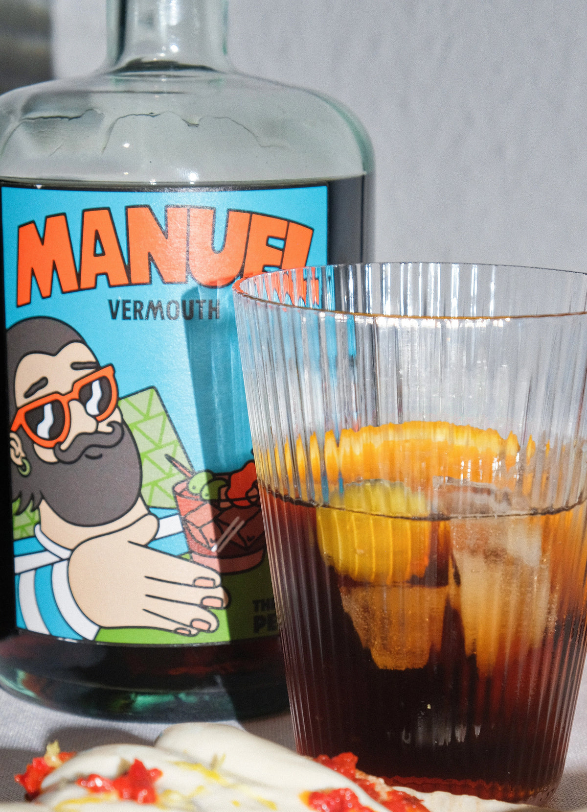 Vaso con vermouth Manuel junto a su botella.