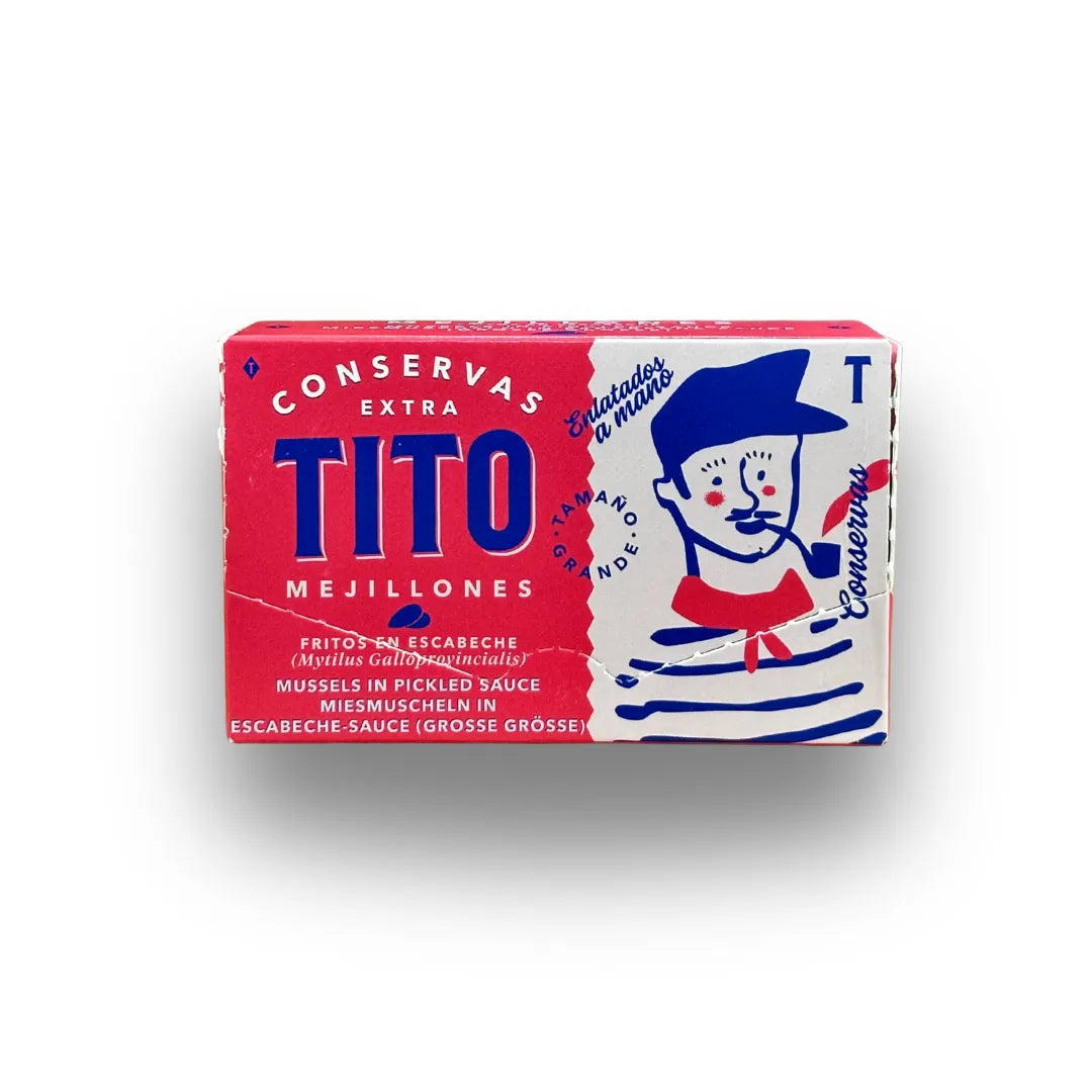 Estuche de mejillones de Conservas TiTo sobre fondo blanco de estudio, de color rojo con tipografía en azul oscuro y la ilustración de un marinero tradicional en uno de los laterales en D'12 Gourmet