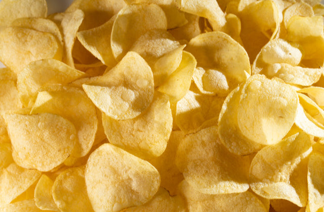 Fotografía de estudio en plano detalle de un conjunto de patatas fritas Bonilla a la Vista recién hechas en D'12 Gourmet. La toma resalta el característico corte fino y ondulado de la patata seleccionada, su apetitoso tono dorado uniforme y una textura visiblemente crujiente y ligera, libre de exceso de aceite y sazonada de forma equilibrada con sal marina.