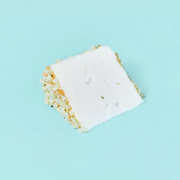 Sobre fondo azul una cuña de queso de la casa Quesos Cerrón, un queso de cabra ecológico afinado con almendras y miel.