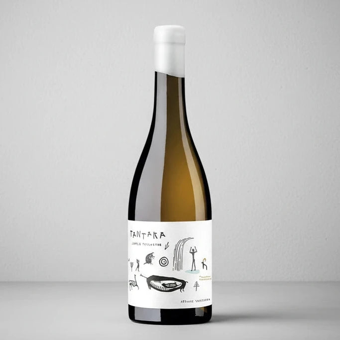 Botella de vino blanco Tantaka Txakoli (D.O. Arabako Txakolina) sobre fondo blanco de estudio, con etiqueta de color blanco e ilustraciones de trazos rupestres de estilo prehistórico en D'12 Gourmet