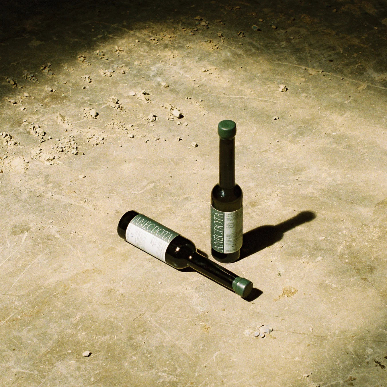 En un suelo de hormigón se ven dos botellas de aceite de oliva virgen extra Lagravera de la marca Anècdota.