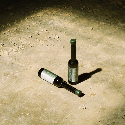 En un suelo de hormigón se ven dos botellas de aceite de oliva virgen extra Lagravera de la marca Anècdota.