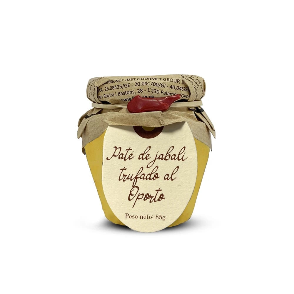 Tarro de cristal sobre fondo de estudio con paté de jabalí trufado al Oporto de la marca La Cuna, permitiendo apreciar la calidad del producto en su interior, con la tapa cubierta en papel kraft y atada con una cuerda de la que cuelga una etiqueta de papel marrón con la información del producto en D'12 Gourmet