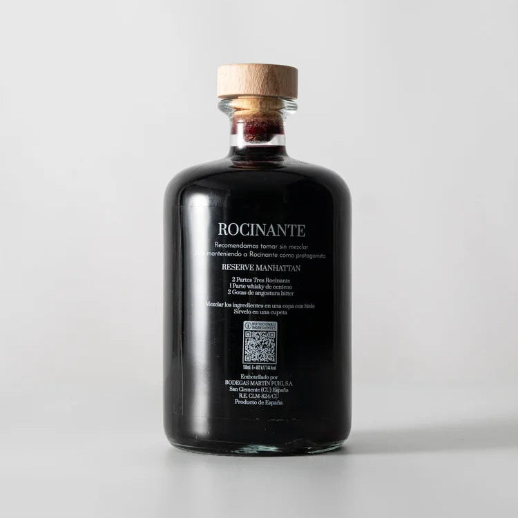 Una botella en el centro de la imagen, la parte de atrás del vermut Tres Rocinante donde se puede ver en blanco las recomendaciones y datos del vermut.