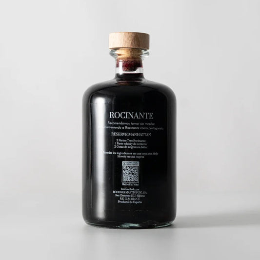 Una botella en el centro de la imagen, la parte de atrás del vermut Tres Rocinante donde se puede ver en blanco las recomendaciones y datos del vermut.