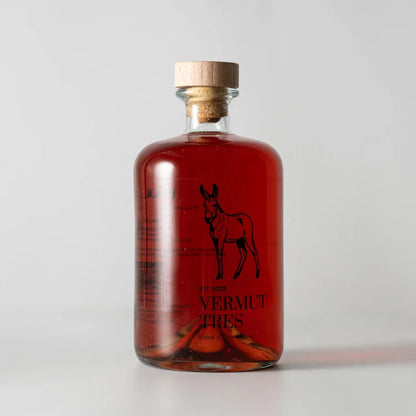 En el centro de la pantalla vermut Tres Rucio, botella de vermut rosado y en el centro un burro y debajo en letras en negro Vermut Tres.