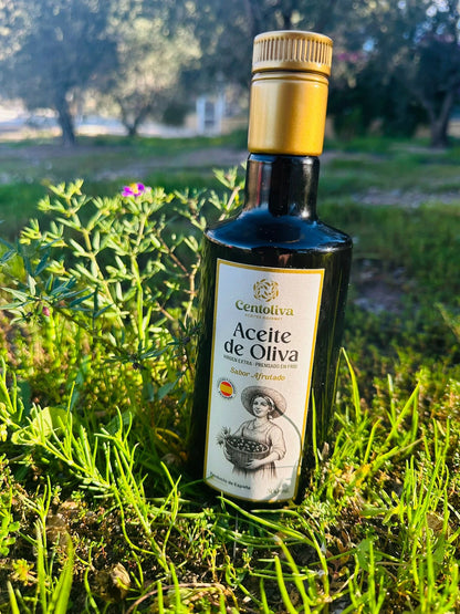 Botella de aceite de oliva Centolovia, producto de la Región de Murcia, sobre césped. Envase de diseño tradicional con etiqueta que presenta una ilustración en blanco y negro de una mujer con una cesta de aceitunas y la información de la marca.