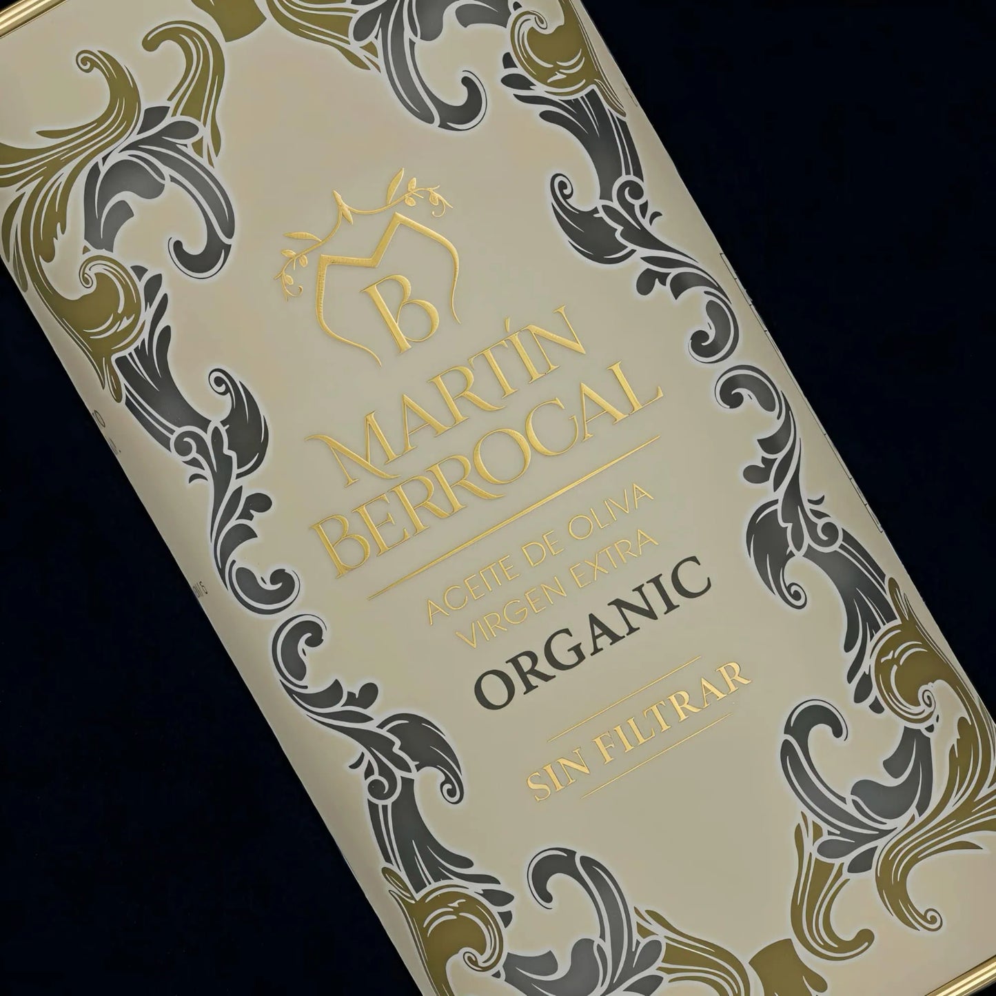 Primer plano de la botella de aceite de oliva virgen extra sin filtrar Martín Berrocal, con una etiqueta de estilo barroco en tonos blancos, decorada con motivos vegetales en azul y verde. En el centro se aprecia el nombre de la marca y la información del producto.