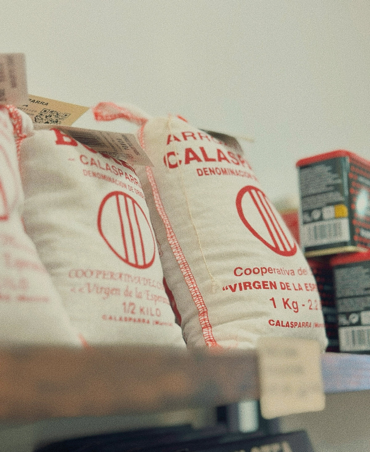 Sacos de tela blanco de arroz redondo y bomba con D.O. Calasparra expuestos en las estanterías de madera de la tienda D'12 Gourmet