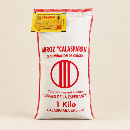 Saco de tela blanco con arroz redondo D.O. Calasparra sobre fondo de estudio, destacando la tipografía, información del producto y logotipo impresos en rojo en D'12 Gourmet
