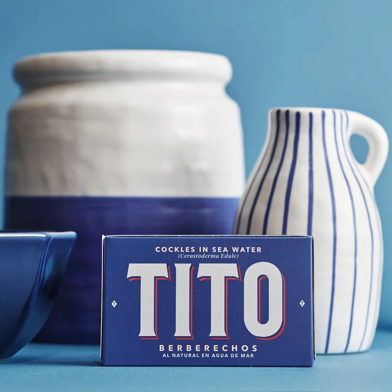 bodegón azul con diferentes jarrones, faro y en el centro una lata de conservas Tito de color azul con letras blancas.