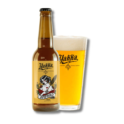 Botella de cerveza artesana de Murcia de trigo con etiqueta amarilla acompañada con su vaso sobre fondo blanco