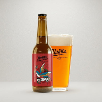 Cereza Yakka tipo Marzen con etiqueta roja acompañada de un vaso con su propia cerveza sobre fondo blanco.