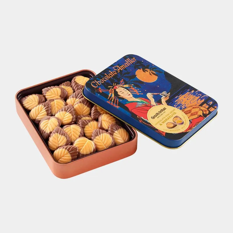 Lata vintage abierta y se ve en su interior hojas de chocolate con leche y maracuyá.