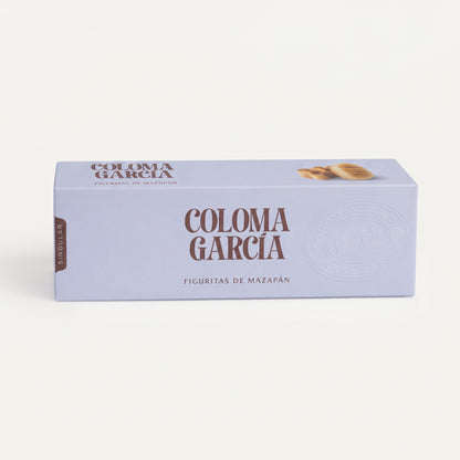 Caja elegante de figuritas de mazapán Coloma García en tono morado suave con letras brillantes sobre fondo de estudio.