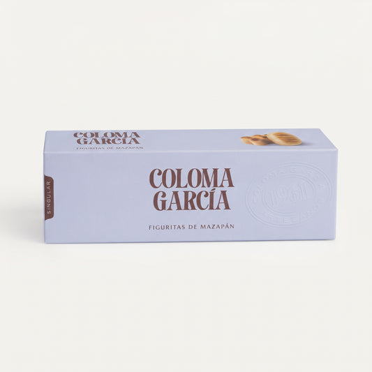 Caja elegante de figuritas de mazapán Coloma García en tono morado suave con letras brillantes sobre fondo de estudio.