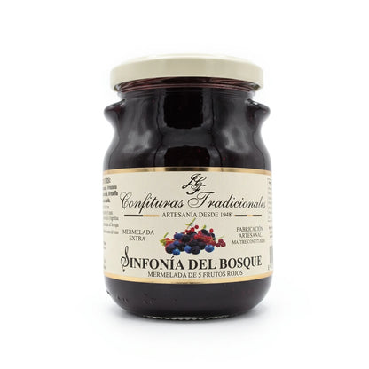 Frasco transparente de confitura tradicionales, la mermelada se llama Sinfonía del Bosque y está compuesta por frutos rojos. La etiqueta blanca, dejando ver la mermelada de frutos rojos y mostrando la ilustración de las frutas junto a la marca.