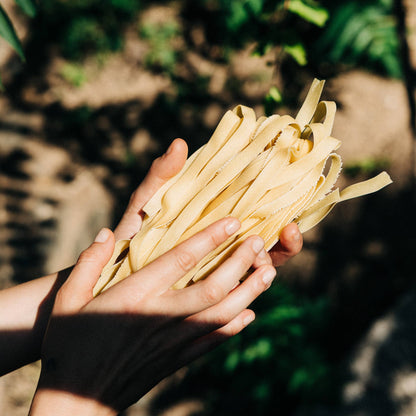 Dos manos sosteniendo pasta griega Hylopites de Creta Yiayia & Friends sin empaque con fondo de campo desenfocado en D'12 Gourmet