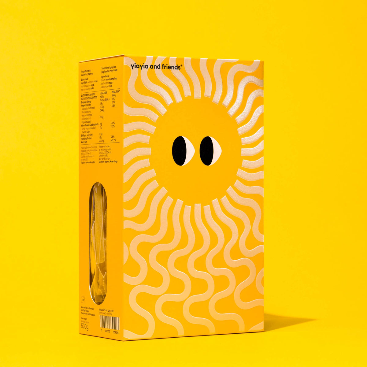 Caja de pasta griega Hylopites de Yiayia & Friends vista de perfil sobre fondo amarillo de estudio, con ventana lateral transparente que muestra la pasta interior en D'12 Gourmet