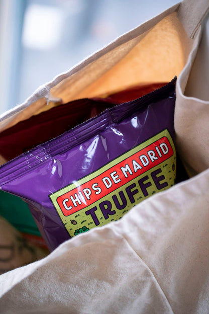 Bolsa de patatas fritas sabor trufa Superbon de color morado asomando de un tote bag en primer plano, mostrando parte del diseño moderno del envase.