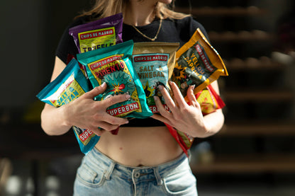 Mujer sosteniendo entre sus brazos diferentes bolsas de patatas fritas de la marca superbon.