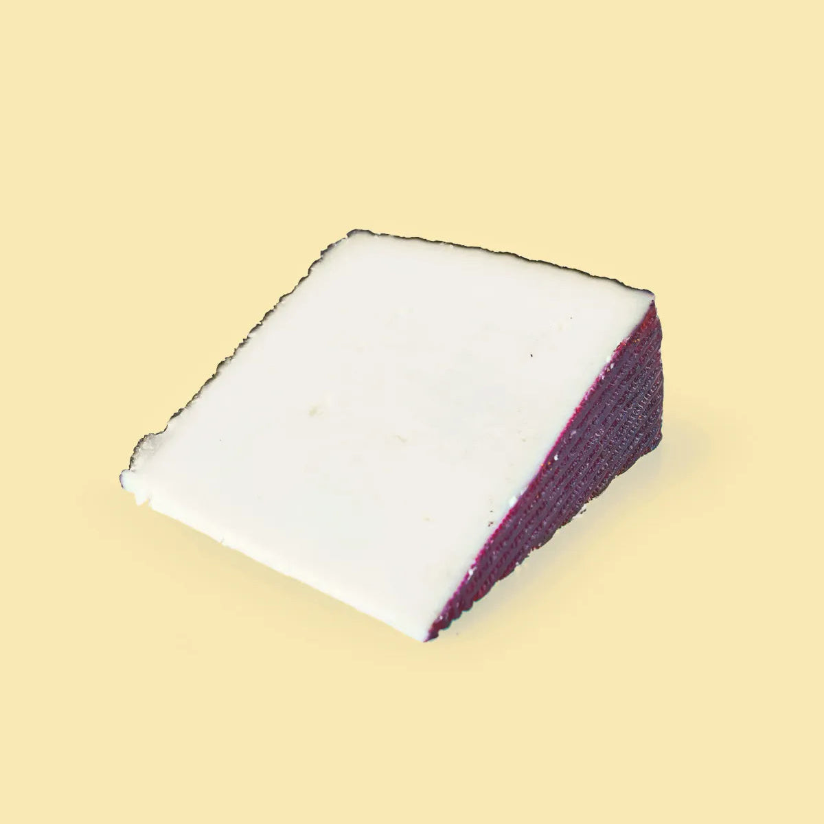 Sobre fondo amarillo una cuña de queso de quesos cerrón, un queso de cabra al vino tinto monastrell. Podemos observar su corteza rojiza del vino y su interior blanco.