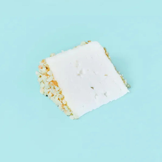 Sobre fondo azul una cuña de queso de la casa Quesos Cerrón, un queso de cabra ecológico afinado con almendras y miel.