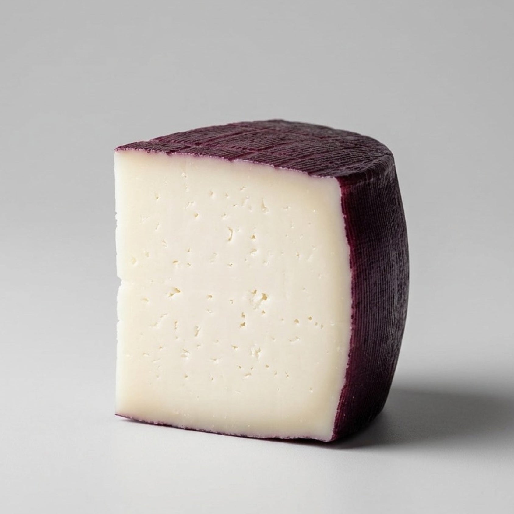 Sobre fondo gris de estudio una cuña de queso de Murcia al vino con denominación de origen protegida.