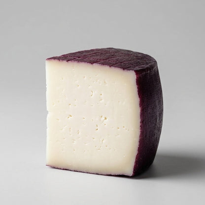 Sobre fondo gris de estudio una cuña de queso de Murcia al vino con denominación de origen protegida.
