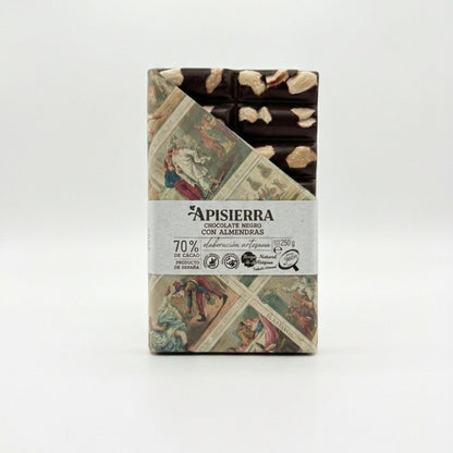 Tabletón de chocolate negro con almendras enteras tostada a mano. Producto realizado de forma artesanal. Vemos el envase con una obertura que nos permite ver el producto y la otra mitad vemos el diseño clásico pero elegante.