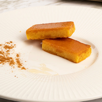Plato blanco con dos trozos de turrón artesanal de yema tostada Coloma García mostrando su textura y dorado superior.