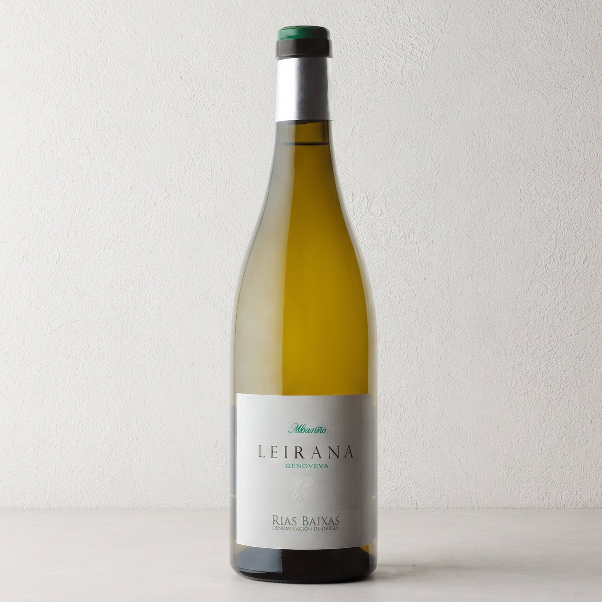 Botella de vino blanco Leirana sobre fondo de estudio. Formato tradicional con etiqueta blanca detallada y cápsula amarilla con la palabra «Genoveva» impresa en blanco.
