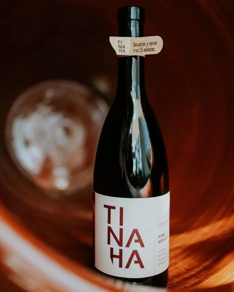 Botella de vino Tinaja colocada dentro de una tinaja tradicional de elaboración. Diseño clásico con etiqueta blanca y la palabra «TINAJA» en letras rojas divididas en tres líneas.