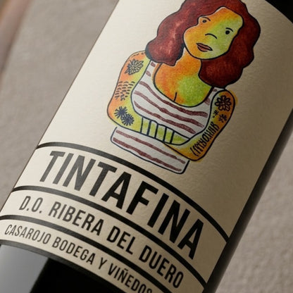 Detalle de la etiqueta del vino tinto Tintafina de Casa Rojo con ilustración de una mujer tatuada, el nombre del vino en grandes letras negras y la indicación D.O. Ribera del Duero junto a Casa Rojo Bodegas y Viñedos.